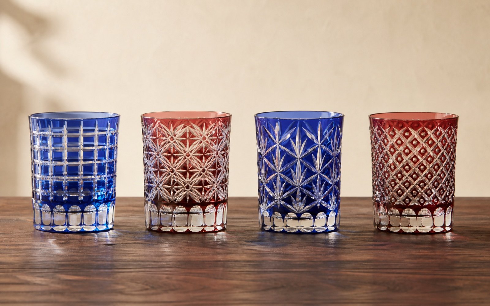 Four Edo Kiriko glasses in a row, each cut with a different traditional geometric pattern
